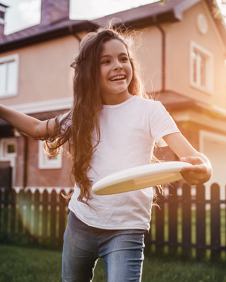 Pretty little girl is playing, having fun and smiling on the backyard on the sunset.